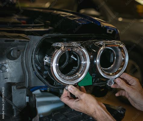 Car headlight in repair close-up. The car mechanic installs the lens in the headlight housing ...