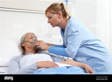 Nurse Puts Oxygen Mask On Elderly Woman Patient Lying In The Hospital