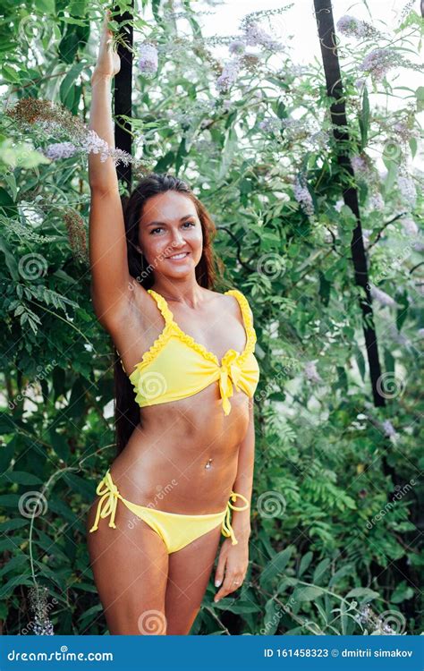 Beautiful Slender Woman In Yellow Swimsuit Sunbathes On The Beach By