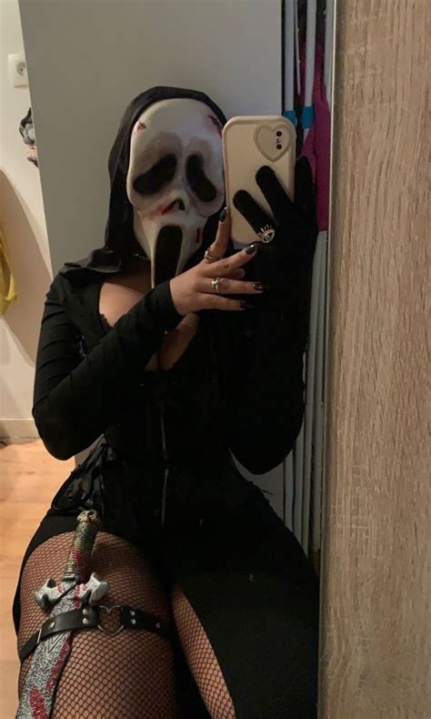 A Woman Wearing A Mask And Holding A Cell Phone In Front Of Her Face