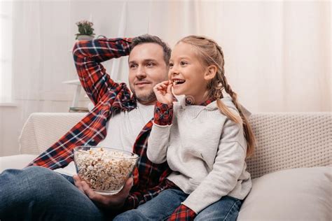 Happy Father And Daughter Eating Popcorn And Watching Tv Together Stock