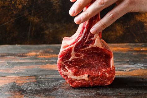 Premium Photo Raw Tomahawk Steak In Butcher Hands