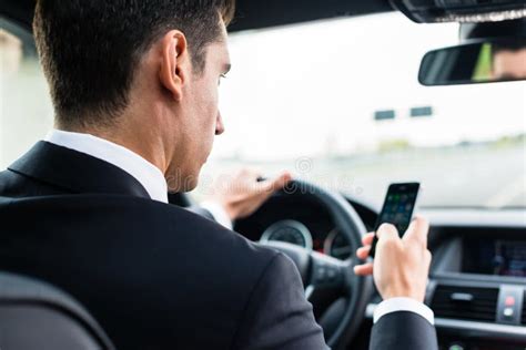 Uomo Che Manda Un Sms Mentre Guidando In Macchina Fotografia Stock