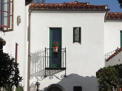 A White Building With Green Shutters And A Balcony