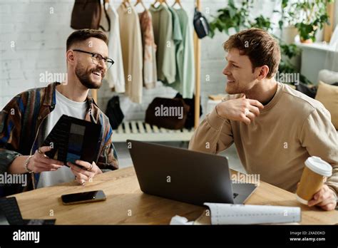 Two Men A Gay Couple Work Together At A Table With A Laptop