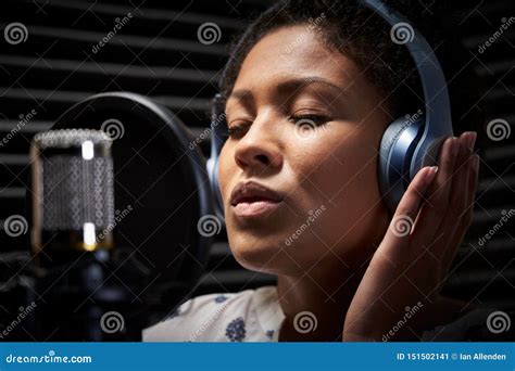 Female Vocalist Wearing Headphones Singing Into Microphone In Recording