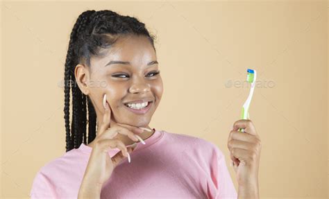 Black Woman Smiles With Perfect White Teeth While Holding A Toothbrush