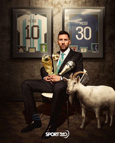 A Man Sitting In A Chair With Two Trophies And A Goat