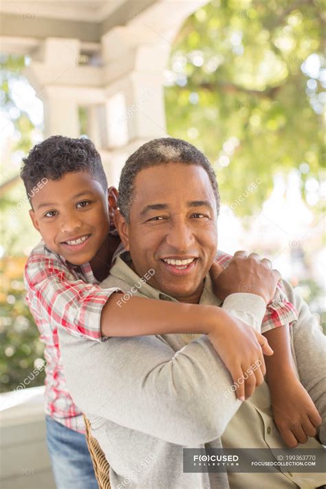 Close Up Portrait Of Smiling Grandfather And Grandson Hugging On Porch