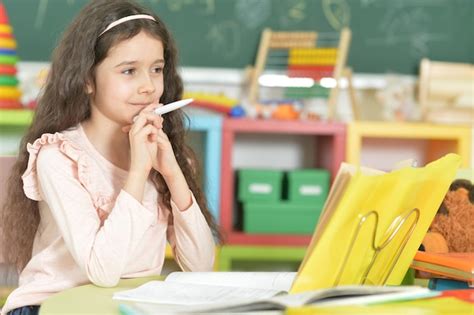 Retrato De Linda Colegiala Haciendo La Tarea En El Aula Foto Premium