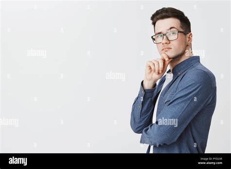 Smart Guy In Glasses And Blue Shirt Standing In Profile Turning At Camera With Thoughtful