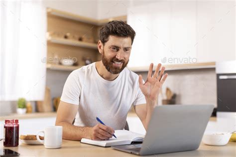 Smiling Mature Caucasian Man With Beard In White T Shirt Waving Hand