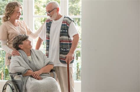 Positieve Vrouw Op Rolstoel Met Gevende Verpleegster En Bejaarde Vriend