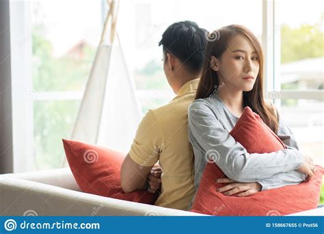 Unhappy Couple Sitting Behind Each Other On The Couch And Avoid Talking