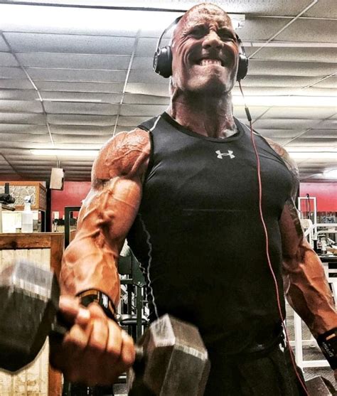 a man with headphones on holding two dumbs in a gym area, and smiling ...