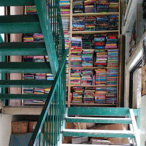 There Are Many Books On The Shelves Next To The Stair Case In This Room