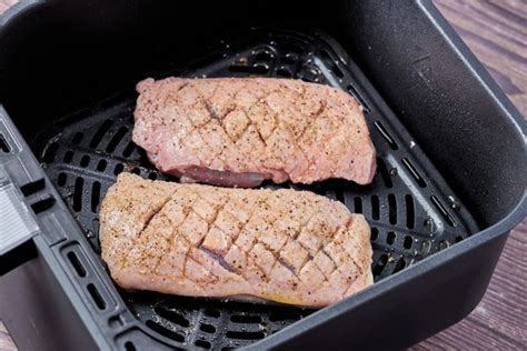 Two Steaks Are Being Cooked In A Grill