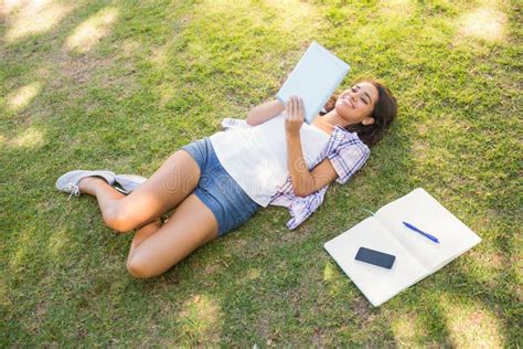 Pretty Brunette Relaxing In The Grass And Reading Book Stock Image