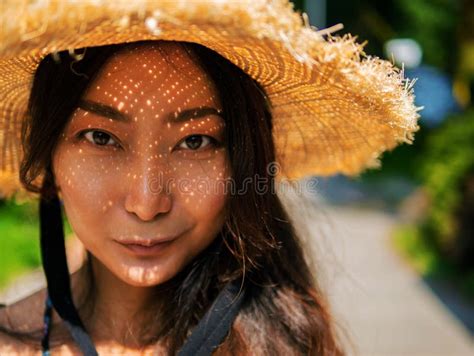 Portrait Of A Beautiful Asian Woman In A Straw Hat Looking At The