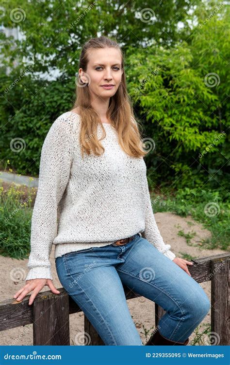 Schöne Junge Blonde Frau Sitzt Draußen Auf Zaun Und Lächelt Stockbild Bild von einsam porträt