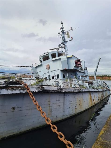 An Old Boat Docked In The Water With Chains Hanging From It S Side And