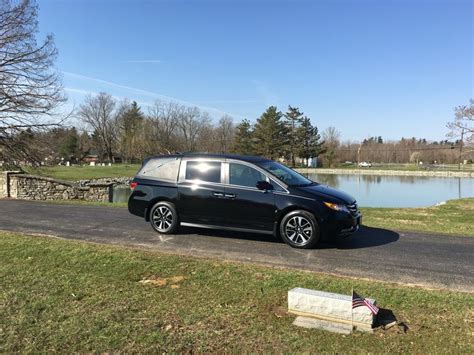 A Black Car Parked On The Side Of A Road Next To A Lake