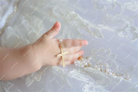 Premium Photo Childs Hand With A Crucifix On A White Cloth