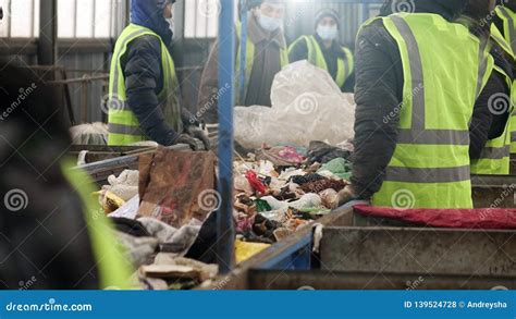 Workers At The Waste Processing Plant Sorting Trash On A Conveyor Belt