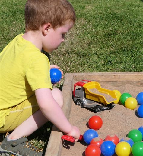 Child Playing Colourful Balls And Buckets In Childs Sand Pit Stock