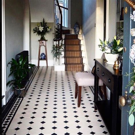 A Hallway With Black And White Tile Flooring Potted Plants On The Stairs