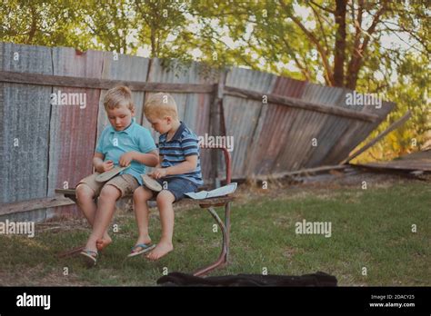 Adorable Blonde Brothers Sitting On A Bench In The Homeyard Stock Photo Alamy