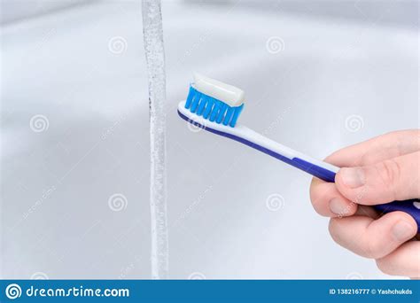 Close Up Image Of A Hand Holding A Blue Toothbrush Water Being Poured