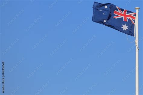 The Australian Flag Flying In The Wind Against A Uniform Clear Blue Sky The Flagpole Mast And