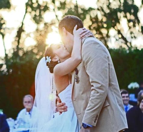 A Bride And Groom Kissing In Front Of An Outdoor Wedding Ceremony As