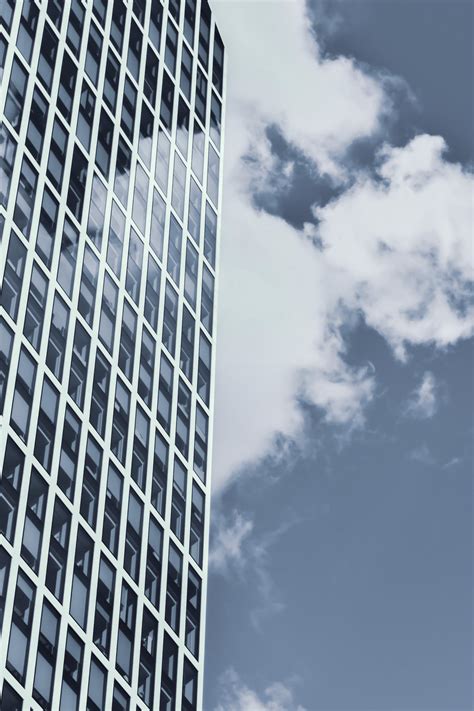 Facade Of Contemporary Skyscraper With Glass Walls Against Cloudy Blue