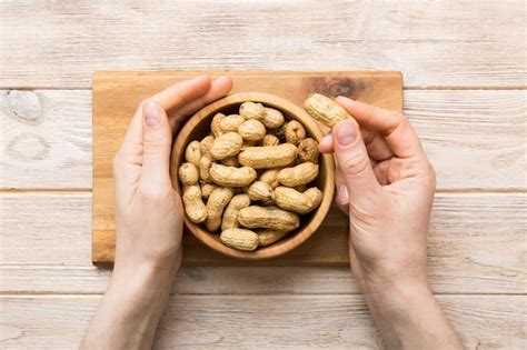 Premium Photo Woman Hands Holding A Wooden Bowl With Close Peanuts