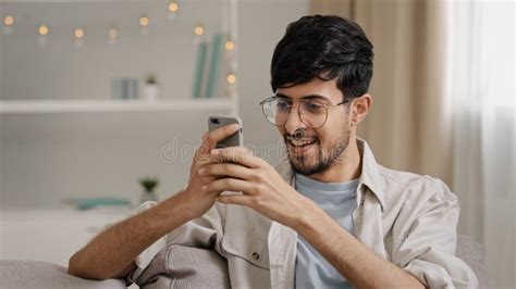 Young 30s Arab Bearded Man Millennial Guy In Glasses Sits At Home On