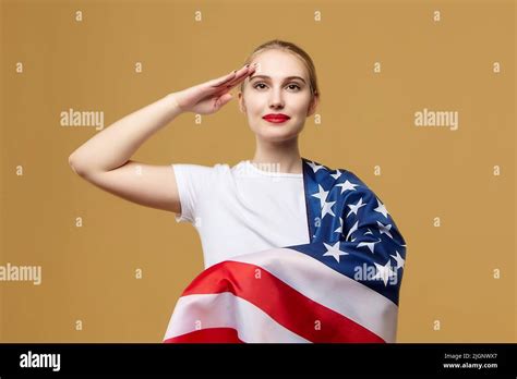 Attractive Blonde Proudly Poses With An American Flag Photo Shoot In The Studio On A Yellow