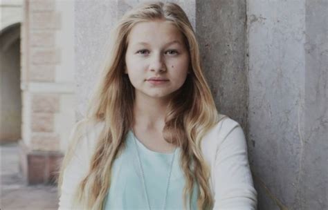 A Woman With Long Blonde Hair Leaning Against A Wall