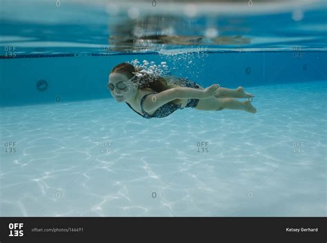 A girl in goggles swims underwater stock photo - OFFSET