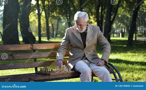 Old Man Sitting On Bench In Park Alone And Playing Chess Retirement