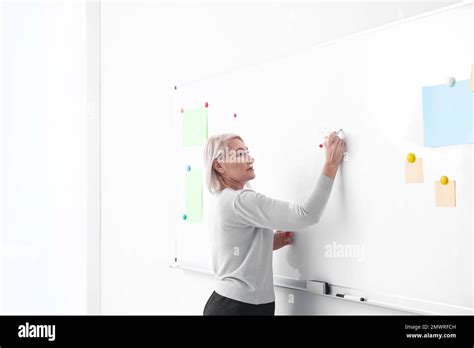 Mature Teacher Writing On Whiteboard In Classroom Stock Photo Alamy