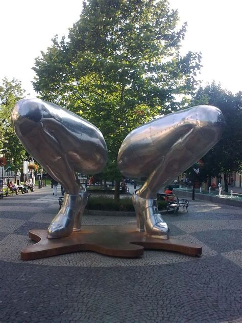 Two Metal Birds Sitting On Top Of A Wooden Stand In The Middle Of A Park