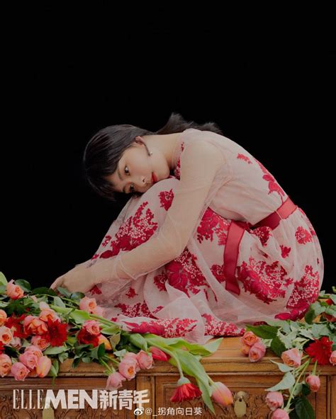 A Woman In A Red And White Dress Sitting On A Table With Flowers Around Her