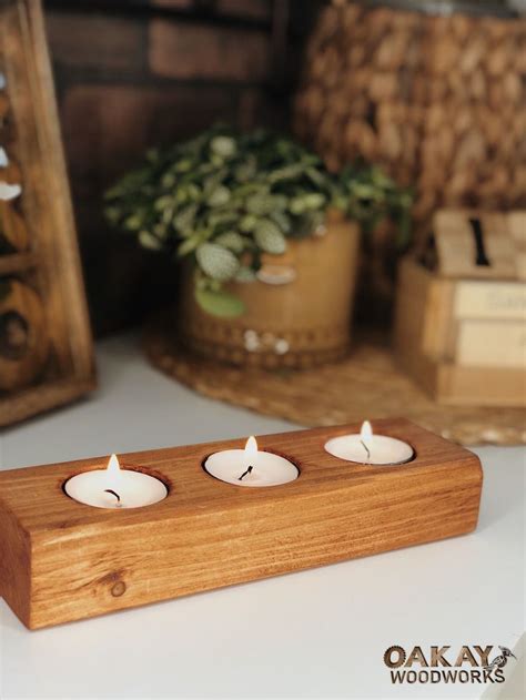 Three Tea Lights Sitting On Top Of A Wooden Stand Next To A Potted Plant