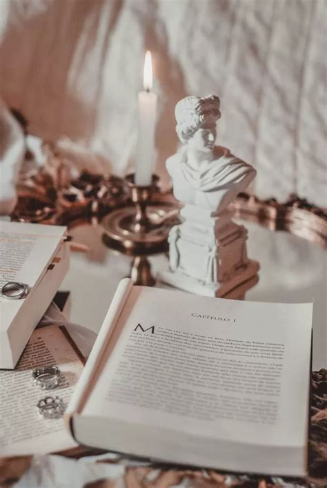 An Open Book Sitting On Top Of A Table Next To A Candle And Some Books