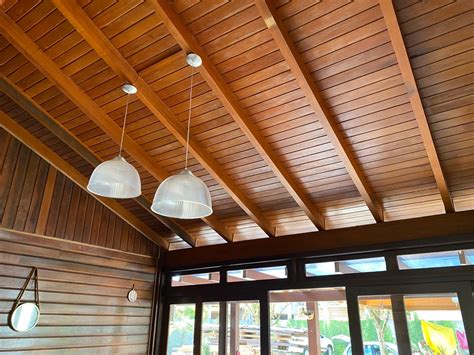 Three Lamps Hanging From The Ceiling In A Room With Wood Paneling And