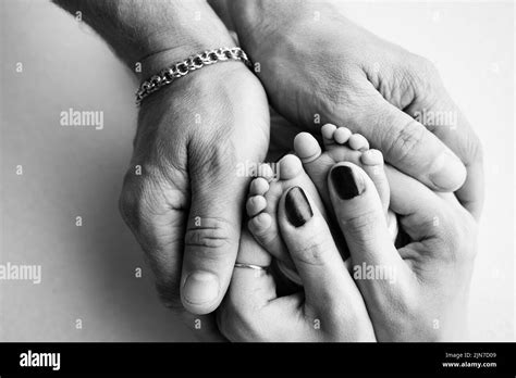 The Palms Of The Parents A Father And Mother Hold A Newborn Baby By