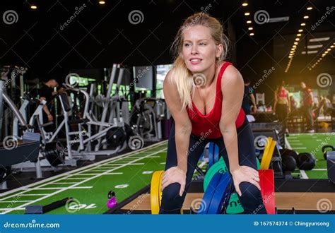 Shot Of Slim Blonde Girl In Sportswear Bending With Her Hands On Knees At The Gym Fitness Woman