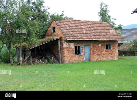 Small Abandoned Red Brick House With Broken Windows And Doors Next To